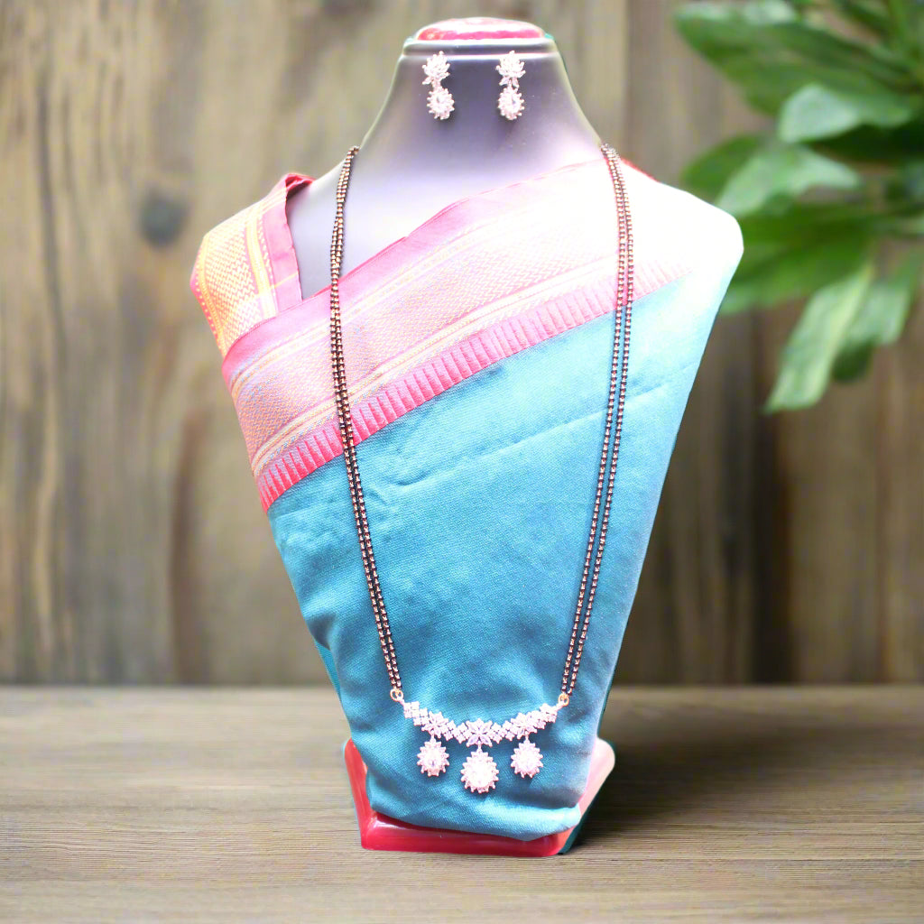 Mannequin wearing a blue and pink saree with jewelry on a wooden surface.