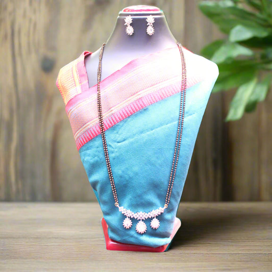 Mannequin wearing a blue and pink saree with jewelry on a wooden surface.